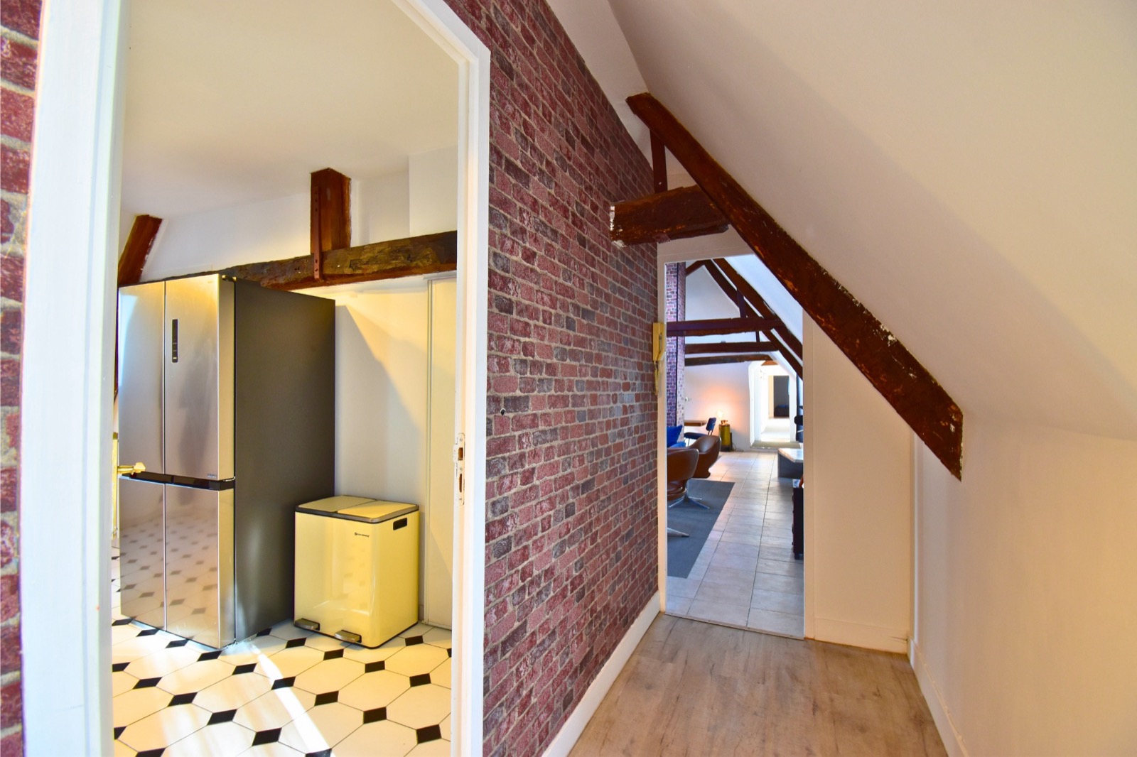 Le Loft des Charpentiers du Roi — couloir avec mur en brique vers le salon