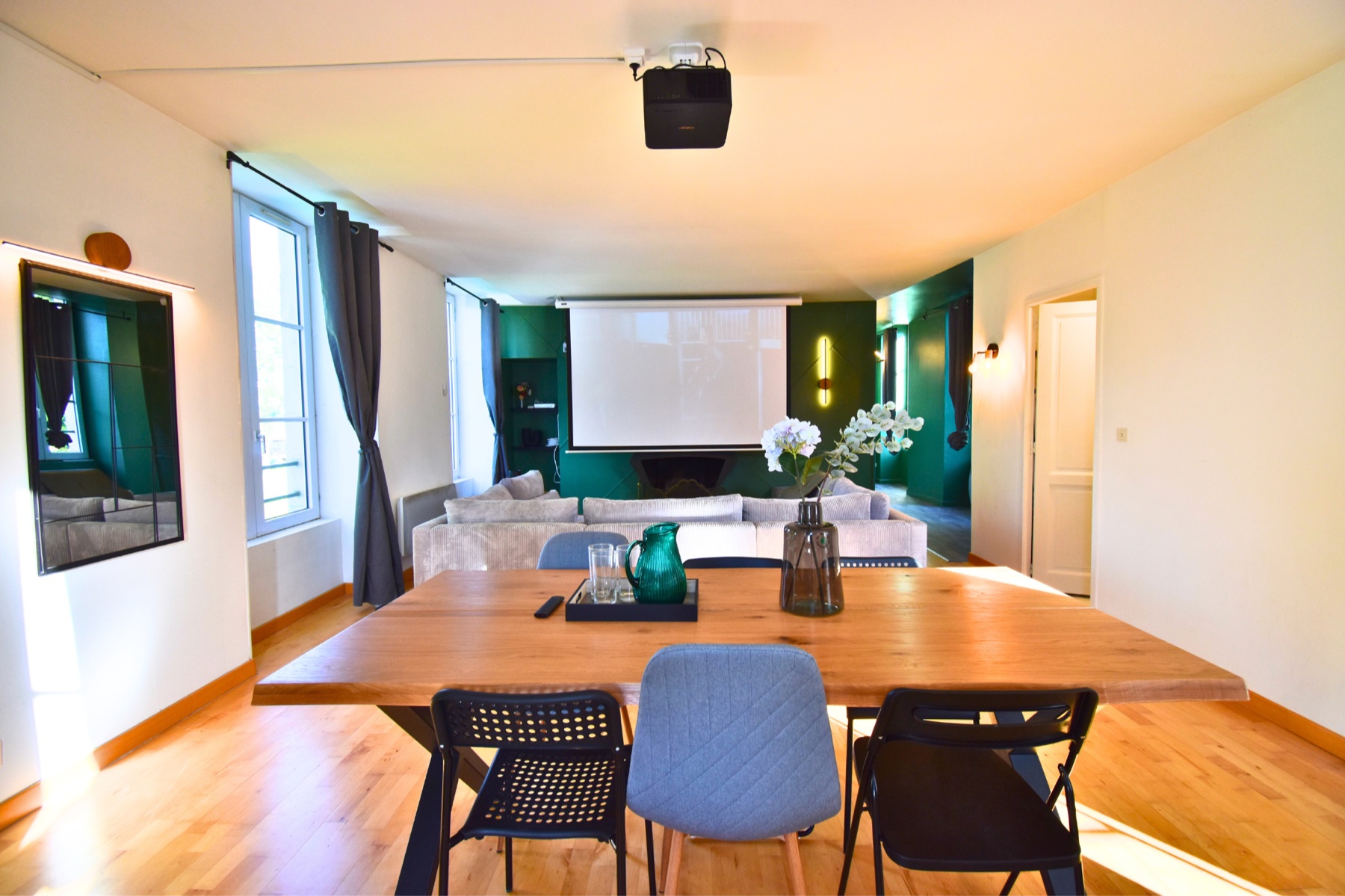 Le Salon Royal — grand séjour avec écran de projection, cheminée et table conviviale